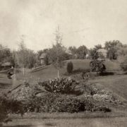Looking north across the “sunken garden” ca. 1910. The two Langdon boys can be seen, one of them perched on the moss rock bridge over Butcher Creek. Whitman Archives photo.
