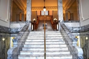 The marble staircase ascends from the entry midpoint between the first and second floor to the third floor. Divided smaller stairs on each side of the photo descend one-half floor to the main level. 